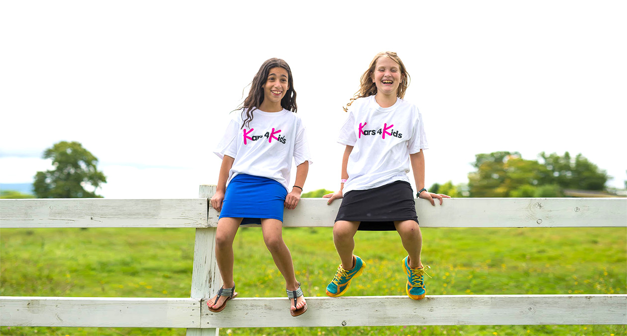 Kars4Kids - Fun at camp two girls sitting and wearing kars4kids tshirts