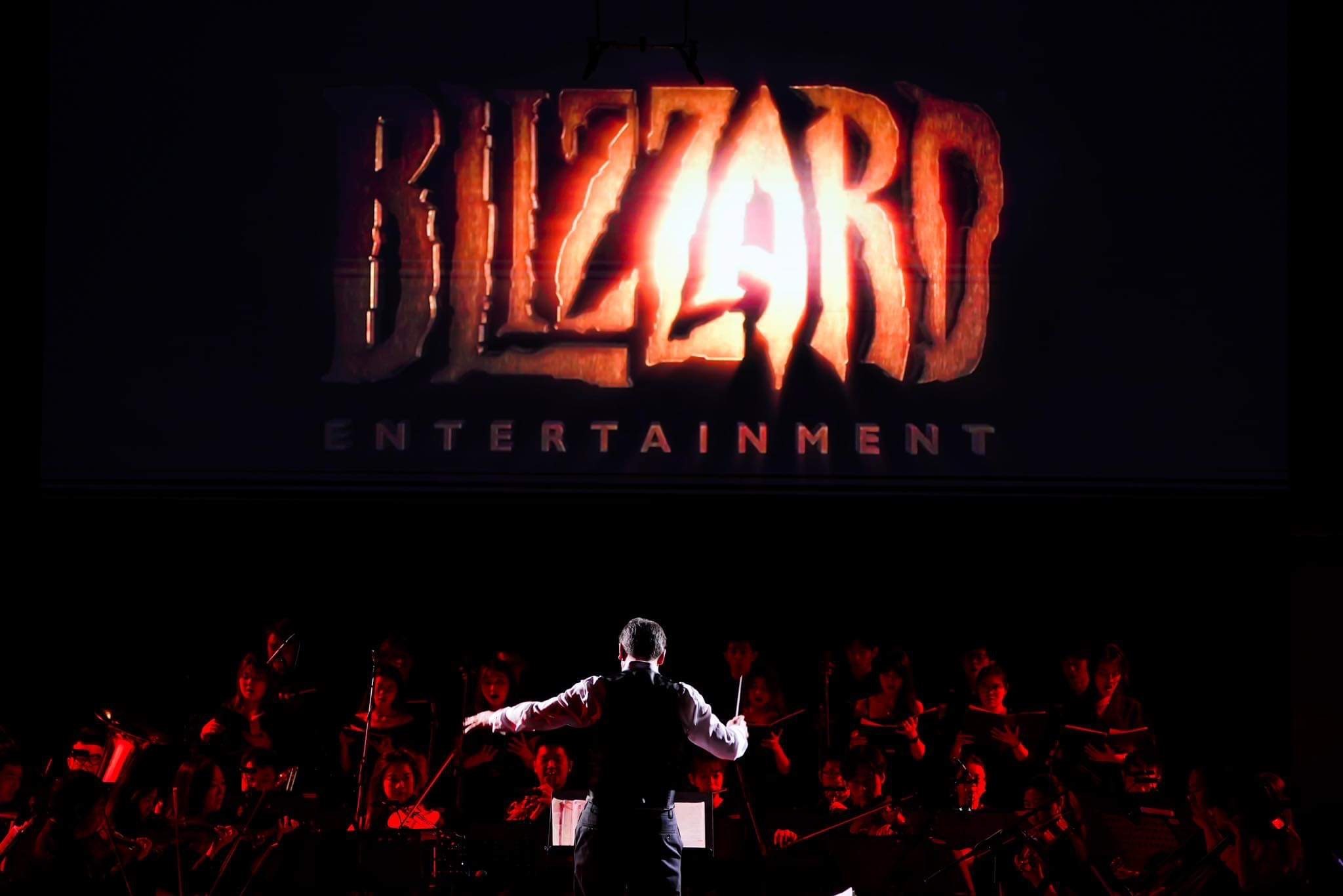 Jason Hayes conducts symphony orchestra with backdrop of "Blizzard Entertainment"