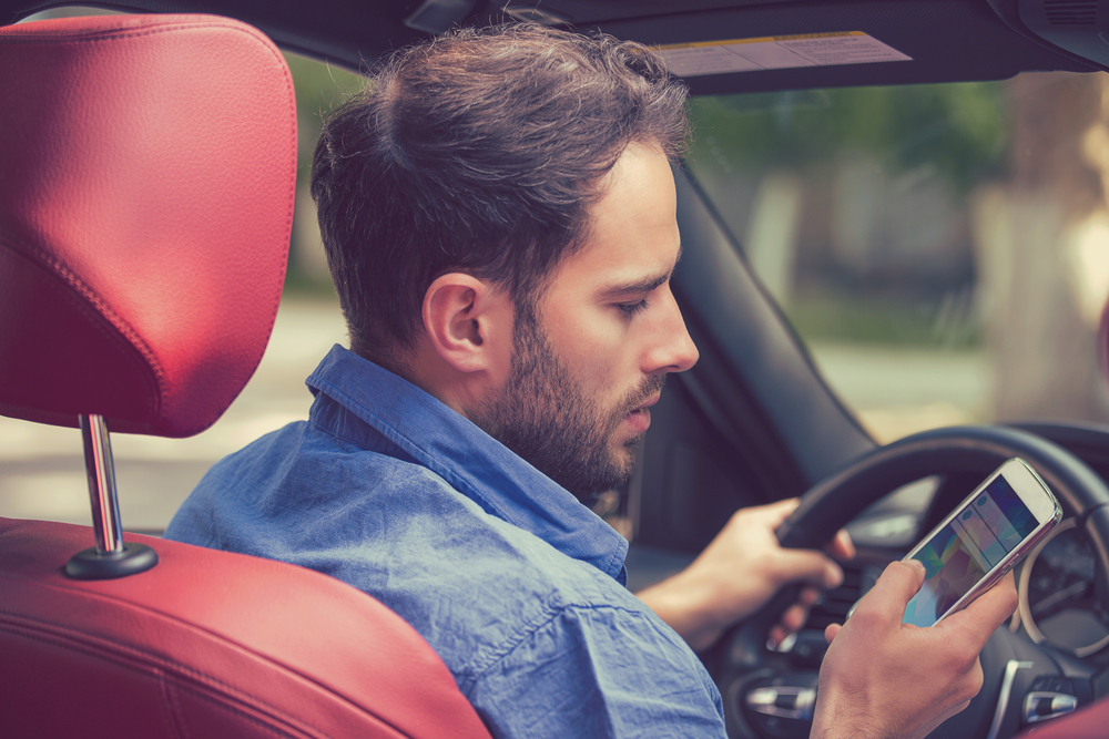 Distracted Male driver looks down at cell phone while driving