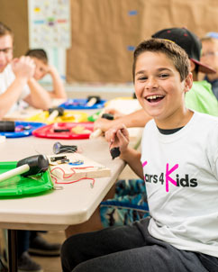 A young boy smiling as he does an arts and crafts project
