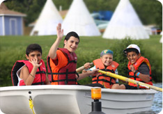 A counselor and his campers boating on a lake
